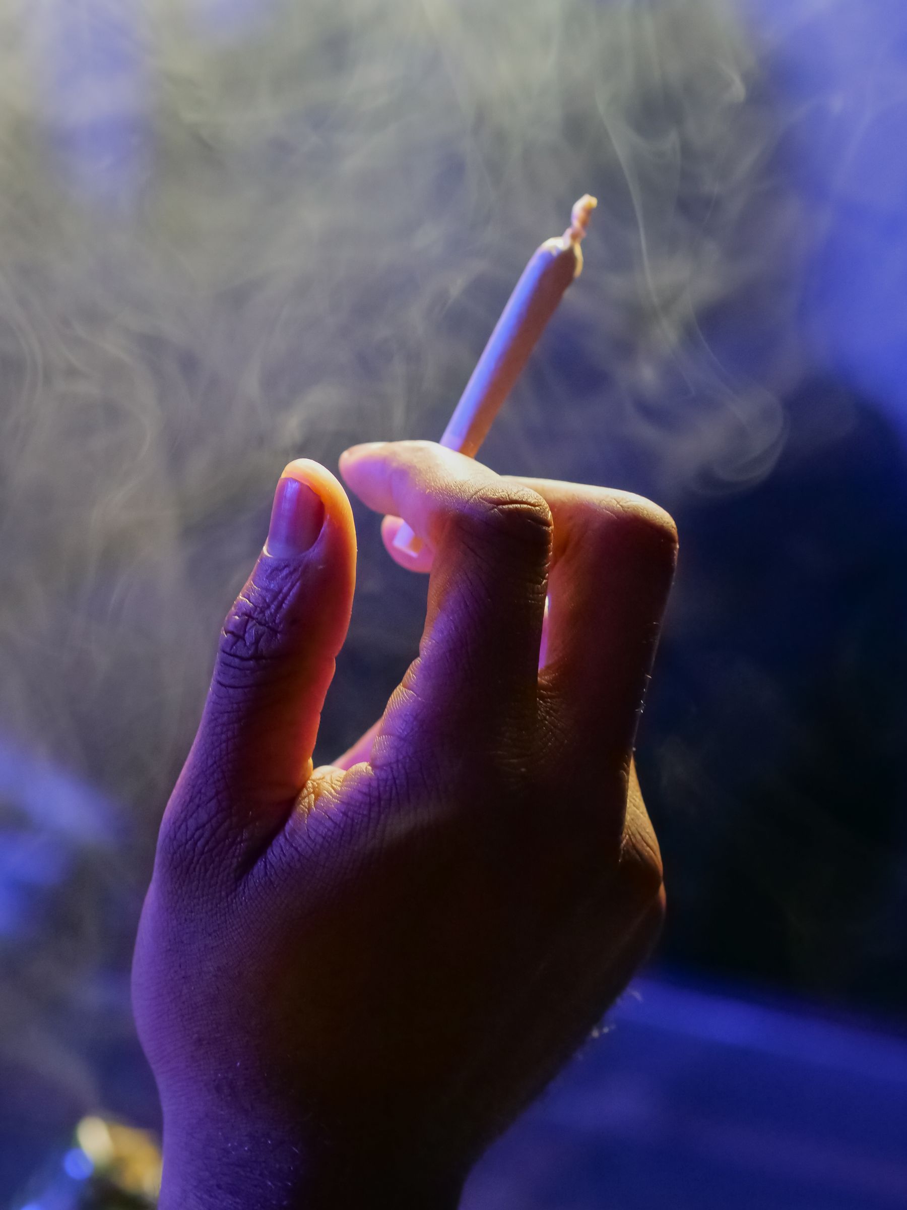 An adult holding a lit cannabis joint